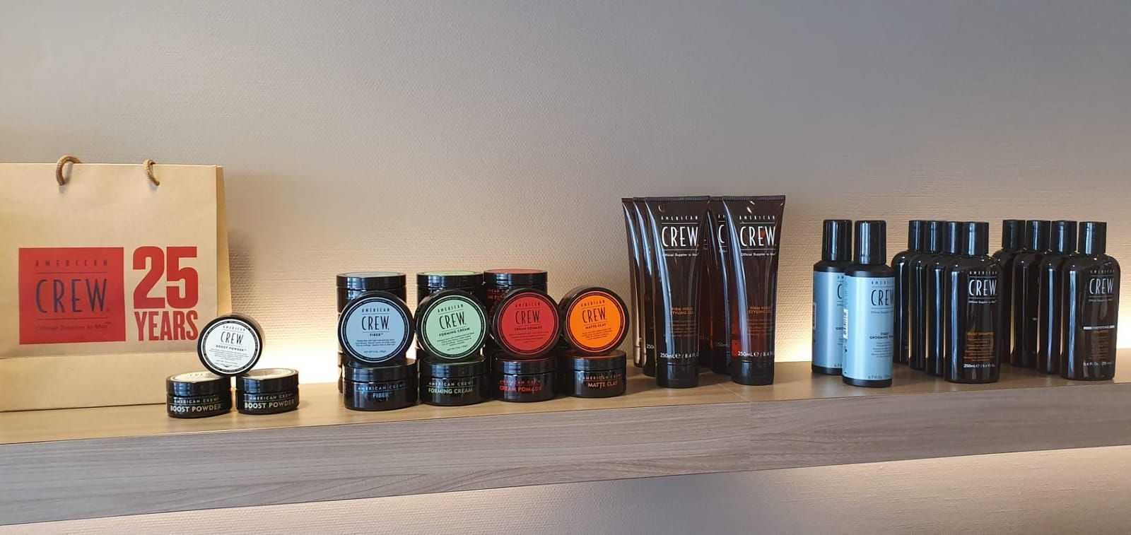 De verlichte wandplank in het salon met American Crew styling wax, pomade, gel en shampoo