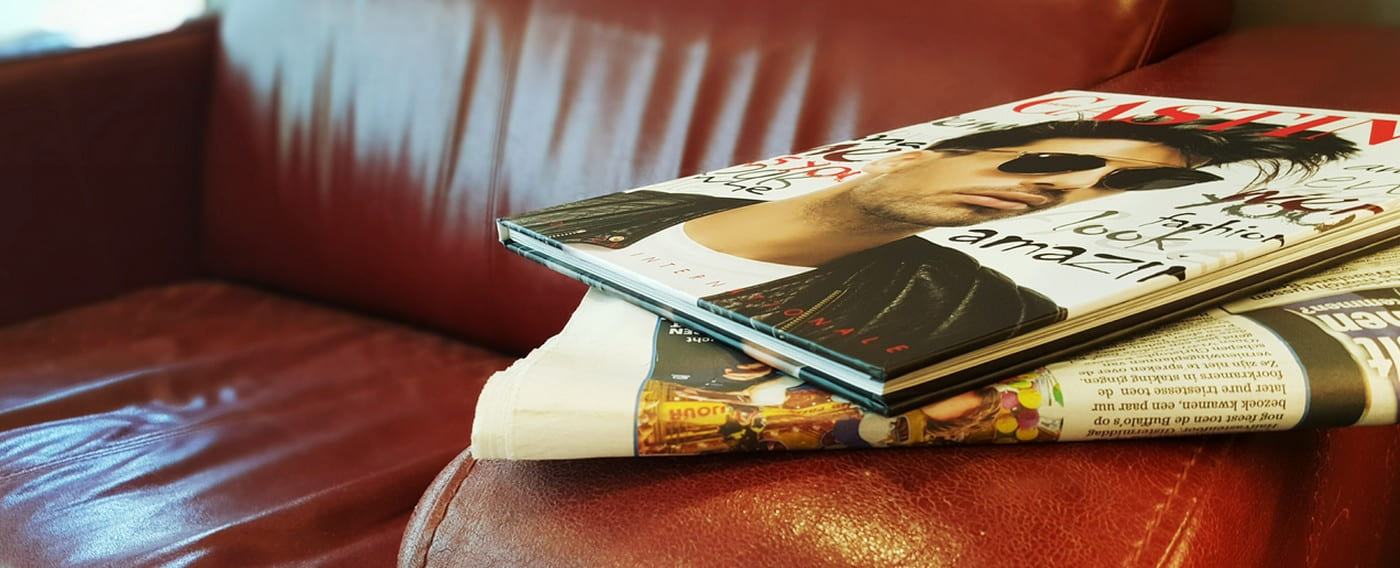 Magazines op de rode leren zetel in de wachthoek van Kapsalon Robert